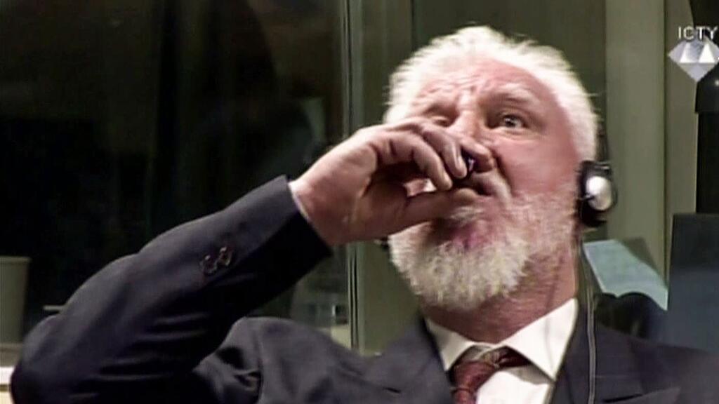 Praljak nahm einen Schluck aus einem kleinen dunklen Fläschchen oder Becher.