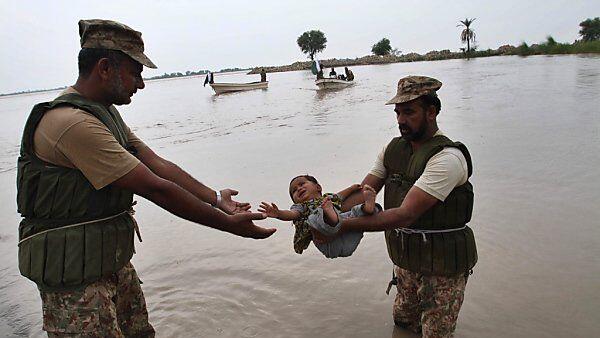Pakistanische Rettungskräfte bringen ein kleines Kind in Sicherheit
