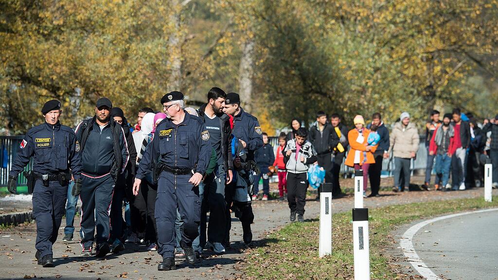 Polizisten geleiten Flüchtlinge zur Grenze zwischen Oberösterreich und Passau.