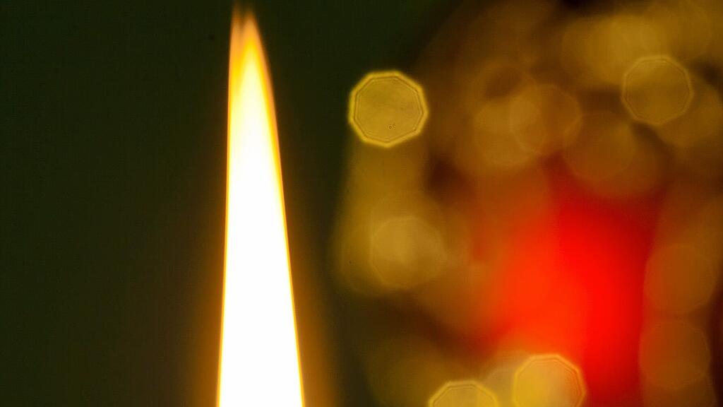 Die Frau warf eine Kerze ins Feuer.
