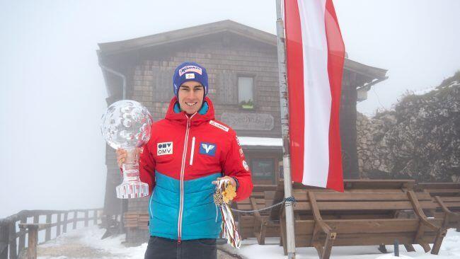Stolz posiert Österreichs Skisprung-Ass mit der Kristallkugel und Edelmetall vor der Hochalm am Untersberg.