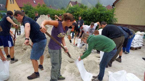 Freiwillige Helfer füllen Sandsäcke