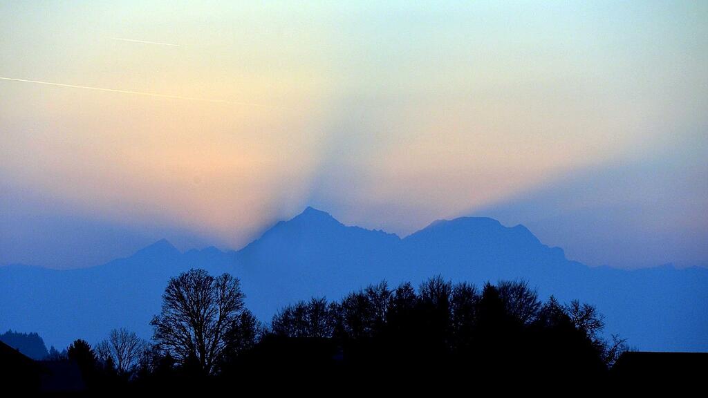 Die Strahlen der untergehenden Sonne ragen hinter dem Tennengebirge hervor. Foto aufgenommen am 16. November in Henndorf (Flachgau).