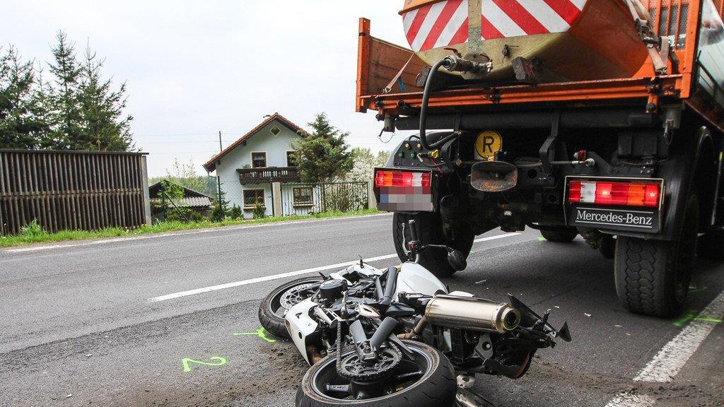 Biker schlittert unter Lkw