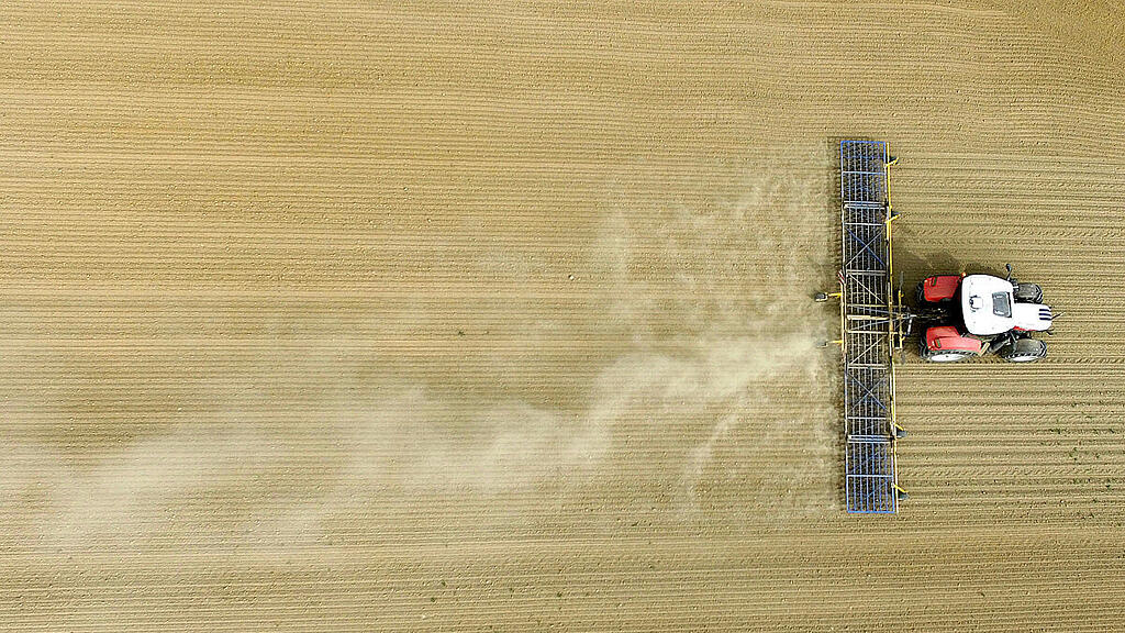 Ein Landwirt beim Eggen eines Ackers